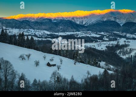 Spectacular winter dawn scenery with high snowy mountains. Majestic sunrise and snowy mountain ridge in background, Piatra Craiului mountains, Carpath Stock Photo