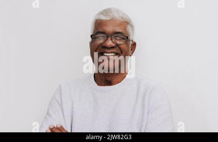 Happy senior man smiling at the camera while standing against a white background. Portrait of a cheerful mature man wearing eyeglasses. Stock Photo