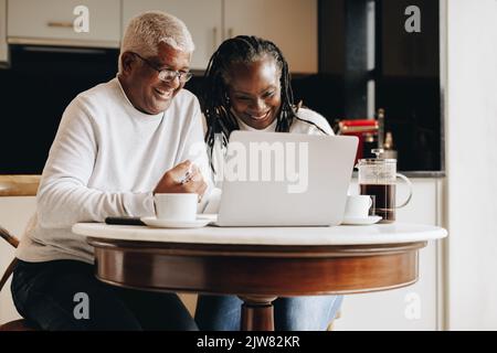 Cheerful senior couple having a video call on a laptop at home. Mature couple having a virtual meeting with a retirement consultant. Happy senior coup Stock Photo