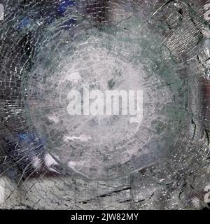 Bulletproof glass after test. bulletproof glass with cracks and a crater from a bullet hit. Testing of armored glass. Stock Photo