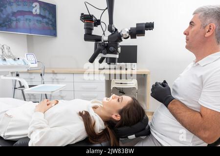 Dentist using dental microscope treating patient with braces in dental office Stock Photo