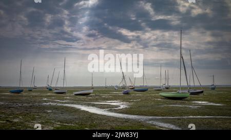 Moored sailing boats lie stranded at low tide in the Thames Estuary next to Essex Yacht Club in Leigh-on-Sea, Essex, UK. Stock Photo