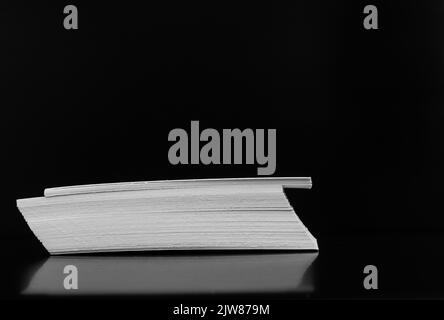 Stack of business cards close-up on black background. Side view. Black and white image Stock Photo