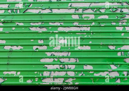 Peeling green paint in messy pattern on corrugated metal surface Stock Photo