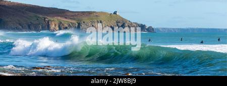 Standing on the beach at Praa Sands Cornwall watching the surfers catching the clear summer waves. Stock Photo
