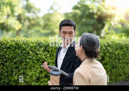 Portrait of young and senior business people working together with digital tablet outdoor. Stock Photo