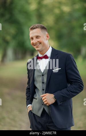 Vertical portrait laughing, confident handsome smiling blond businessman or groom in formal wear in natural parkland Stock Photo