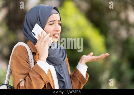 Muslim woman talking to mobile with worried expression Stock Photo