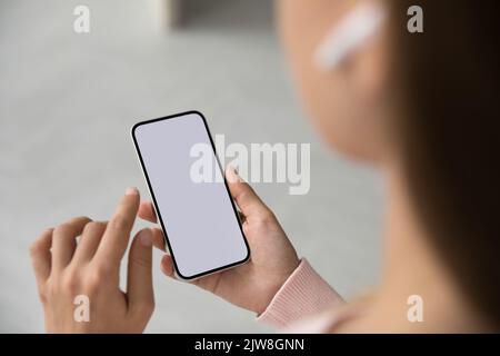 Millennial woman with wireless earphone in ear using mobile phone Stock Photo