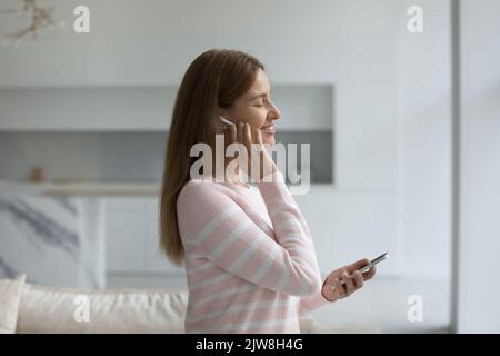 Happy smartphone user listening to ambient music from wireless earphone Stock Photo