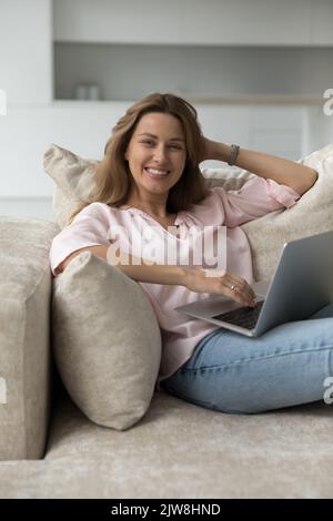 Happy cheerful pretty laptop user woman home vertical portrait Stock Photo