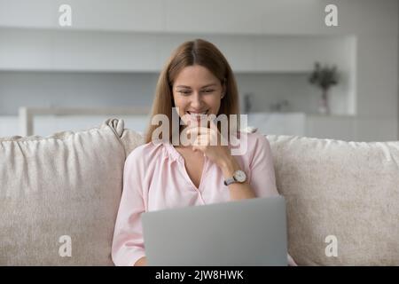 Happy pretty young woman using laptop at home Stock Photo