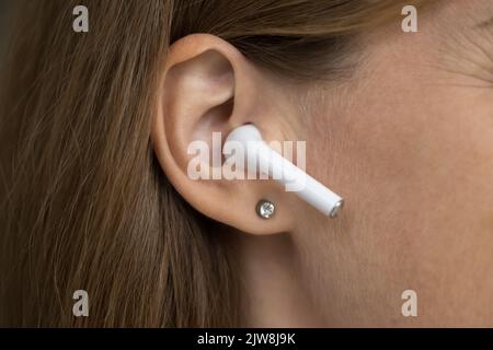Wireless earphone object in female ear close up Stock Photo