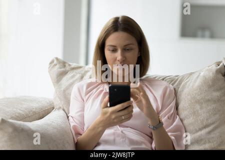 Focused pensive 30s smartphone user woman chatting, typing message Stock Photo