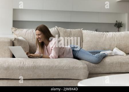 Happy joyful laptop user woman resting on sofa Stock Photo