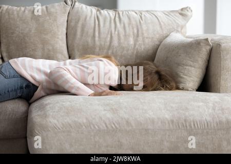 Tired exhausted sleepy young woman lying on belly on couch Stock Photo