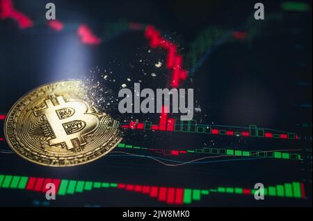 Crypto currency golden coin. Gold bitcoin falling apart. Concept of a cryptocurrency market crisis and defocused chart background. Stock Photo