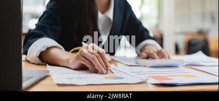 Close up woman hand press calculator to calculate the company's financial results On the wooden table in the office and business work background, tax Stock Photo