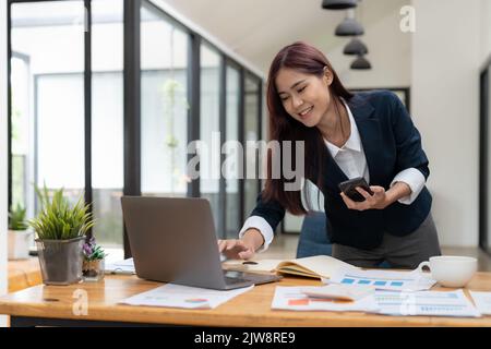Business asian woman using mobile phone during checking an email or social media on internet. accounting financial concept. Stock Photo