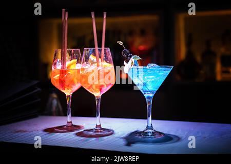Three glasses with fresh alcohol drinks and with ice cubes on the bar counter of a night club - lifestyle concept Stock Photo