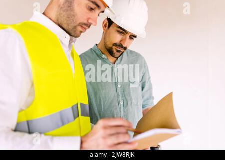 Architect worker discussing with contractor male at construction building site Stock Photo