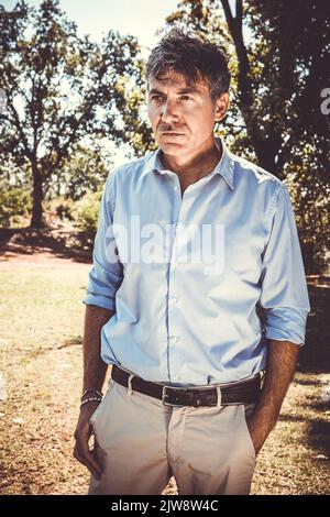 Young man is walking in the park. Beautiful businessman is working outdoors. Stock Photo