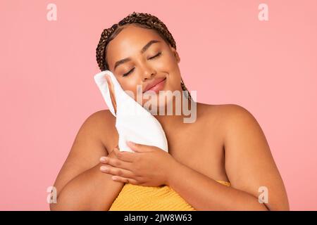 Pretty Overweight Black Lady Drying Face With Towel, Pink Background Stock Photo