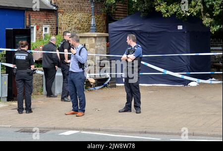 Police officers stand next to a police tent at the scene on at Place de Villerest on the junction of Old Mill Drive and the High Street in Storrington, West Sussex, after a man died. A 68-year-old man has been arrested on suspicion of murder police said. Picture date: Sunday September 4, 2022. Stock Photo