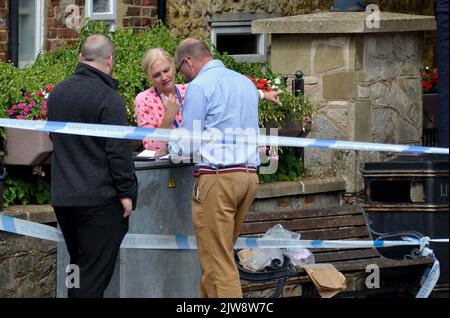 Police officers stand next to a police tent at the scene on at Place de Villerest on the junction of Old Mill Drive and the High Street in Storrington, West Sussex, after a man died. A 68-year-old man has been arrested on suspicion of murder police said. Picture date: Sunday September 4, 2022. Stock Photo