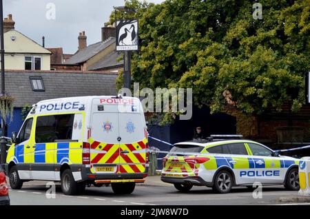 Police officers stand next to a police tent at the scene on the junction of Old Mill Drive and the High Street in Storrington, West Sussex, after a man died. A 68-year-old man has been arrested on suspicion of murder police said. Picture date: Sunday September 4, 2022. Stock Photo