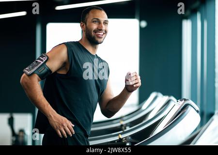 Happy Handsome Young Black Male Athlete Jogging On Treadmill At Gym Stock Photo