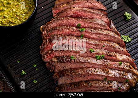 Seared flank steak on a grill pan with chimichurri and horseradish Stock Photo