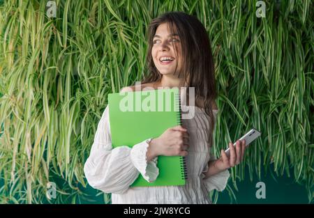Business young woman with a folder on the background of green plants. Stock Photo