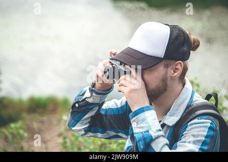 A man takes a photo on a vintage film camera in nature. Stock Photo