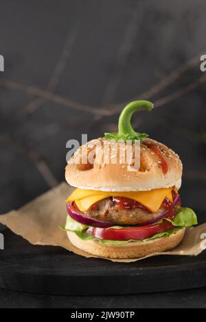 Halloween burger in a shape of pumpkin head jack o lantern on black. Scary cheeseburger on halloween party. Stock Photo