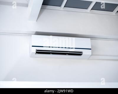White air conditioner on wall background. Wall mounted air conditioner hanging on white wall under the room structure in clean living room in the hous Stock Photo