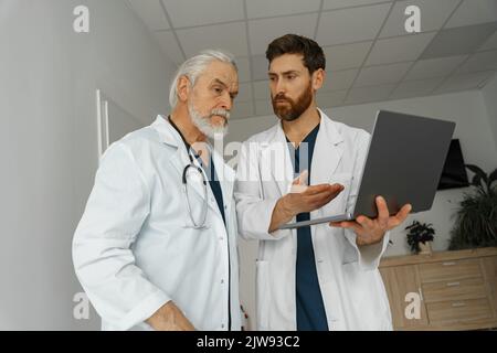 Two doctors are looking at something on the laptop in the doctor's office Stock Photo