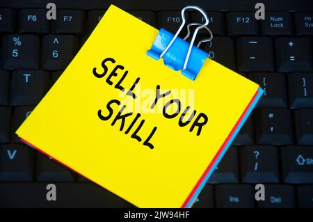 Sell your skill text on yellow notepad on black keyboard background. Stock Photo