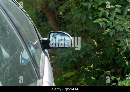 Parked car front door side view mirror seen from behind, detail, closeup, nobody, no people, copy space. Transport, car parts, vehicle parts simple ab Stock Photo
