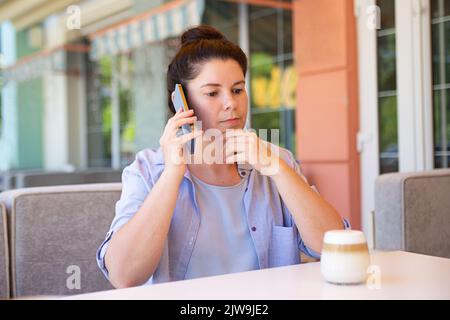 Serious woman with smartphone outside,thinking about something. Stock Photo