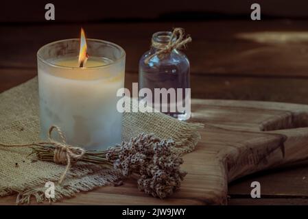 Burning white candle light on old dark wooden table background  burlap sack Halloween Aromatherapy smoke rustic cutting board napkin christmas blue co Stock Photo