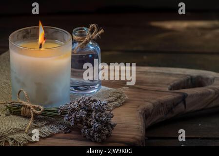 Burning white candle light on old dark wooden table background  burlap sack Halloween Aromatherapy smoke rustic cutting board napkin christmas blue co Stock Photo
