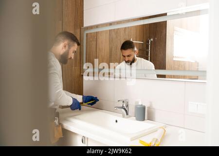 a worker installs a wash basin in a bathroom. Stock Photo