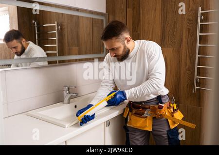 a worker installs a wash basin in a bathroom. Stock Photo