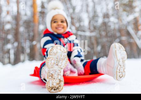 little girl having fun and sledding sled playing in snowy park Stock Photo