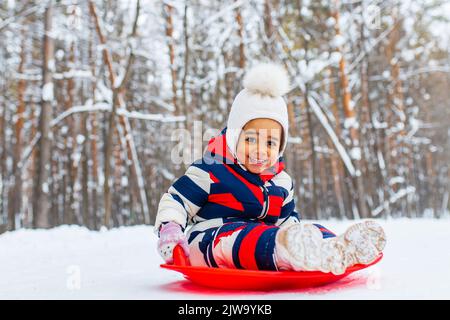 little girl having fun and sledding sled playing in snowy park Stock Photo
