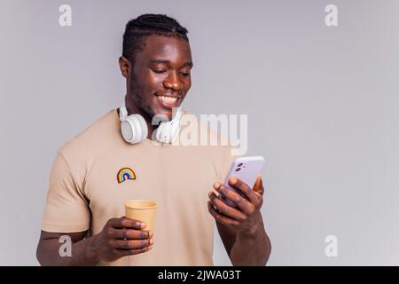 latino man in casual gray t-shirt wearing wireless headphones and using smartphone Stock Photo