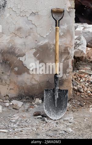 A shovel on the background of a shabby wall of an old house. Stock Photo