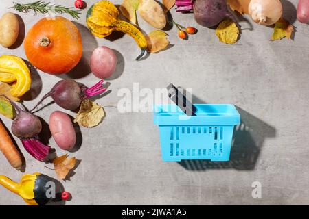 autumn flat lay on a concrete background with pumpkins, beetroot, autumn leaves, autumn leaf, consumer basket and autumn vegetables. Stock Photo