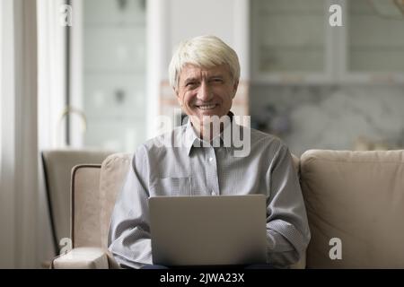 Happy cheerful grey haired business man typing on laptop Stock Photo